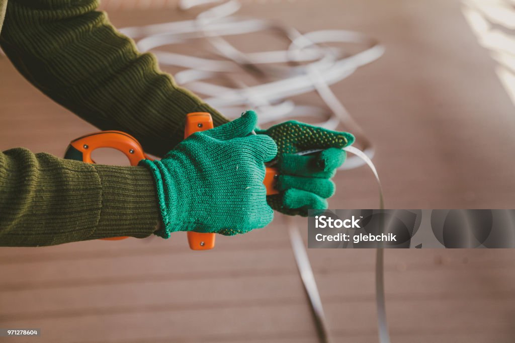 hands in gloves twist the geodetic roulette Hands in green gloves wind a steel band on an orange geodetic roulette Applying Stock Photo