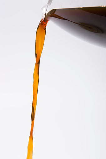 Orange Juice being poured into Glass against White Background