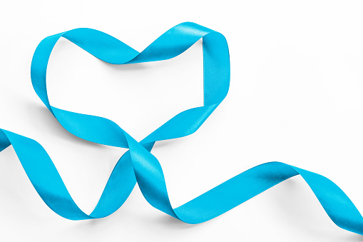 Blue ribbon in heart shape symbolic bow color for prostate cancer awareness campaign and men's health in November (isolated on white background, clipping path)