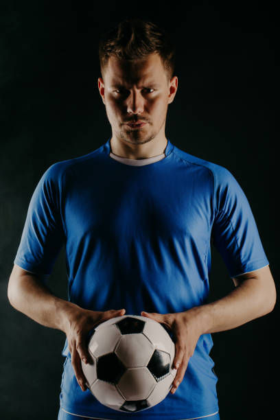 istock Young soccer player with ball on black background in studio 971331522