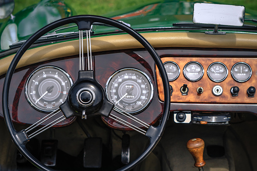 Close-up, detailed photo of the interior, dashboard, steering wheel and speedometer of a classic oldtimer luxury sports car.