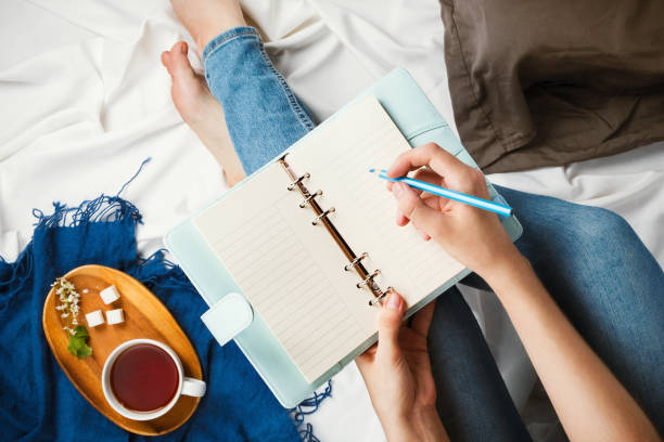istock Flatlay with woman's hands writing in a planner on white sheets with cup of tea aside, social media mockup 971341102