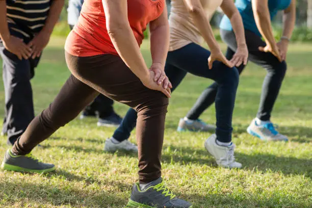 Cropped image of senior people doing lunges in park in the morning