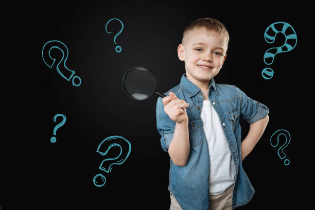 istock Cute boy holding a magnifying glass and looking glad 971360292