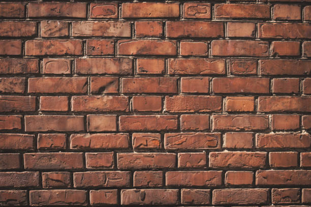 istock Texture of aged red brick wall with cracked weathered structure close-up for designer background 971363108