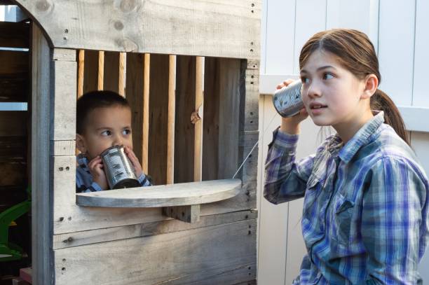 une fille parle à son frère à l’aide d’un téléphone de tin can - tin can phone photos et images de collection