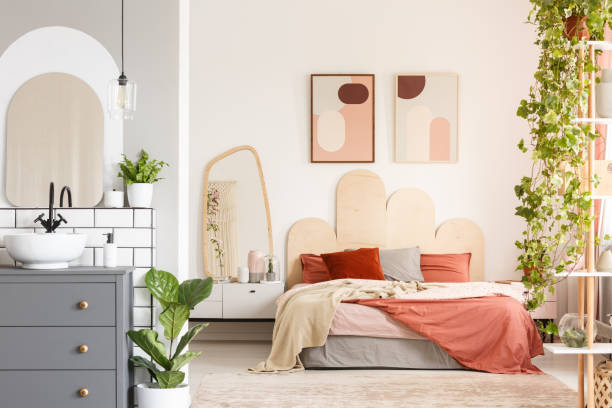 istock Orange pillows on bed next to mirror in modern bedroom interior with posters and bathroom. Real photo 971367426