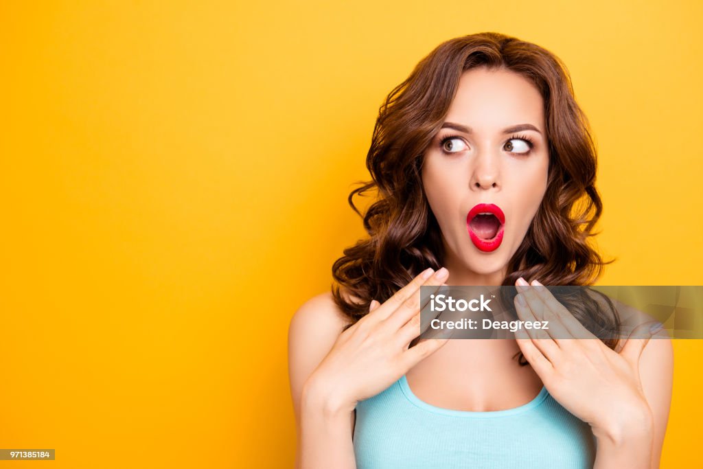 Portrait with copy space for advertisement of shocked afraid woman looking with eyes at empty place having wide open mouth eyes gesturing palms isolated on yellow background Women Stock Photo