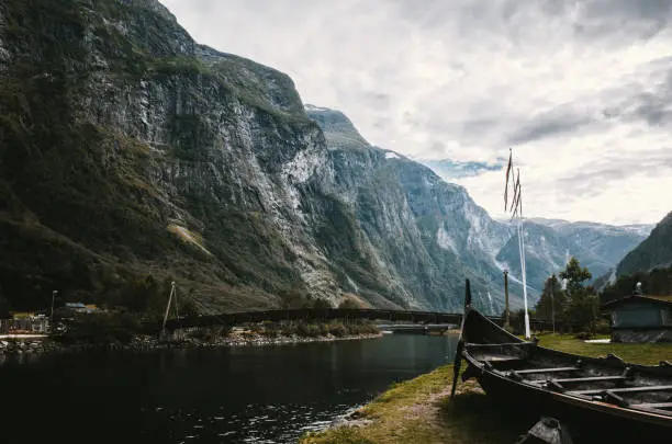 Wooden bridge through the fjord. Old viking boat replica in a Norwegian landscape near Flam, Norway.