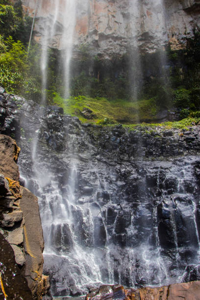 istock Waterfall stream falling from underneath with red rocks and green shrubs 971392238