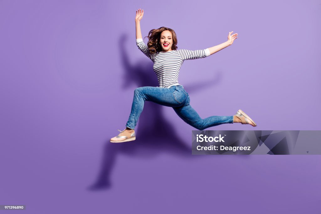 Portrait de folle folle sautant par-dessus en l’air, regardant la caméra ayant bon étirement isolé sur fond violet, concept de mode de vie de personnes vie énergie - Photo de Sauter libre de droits