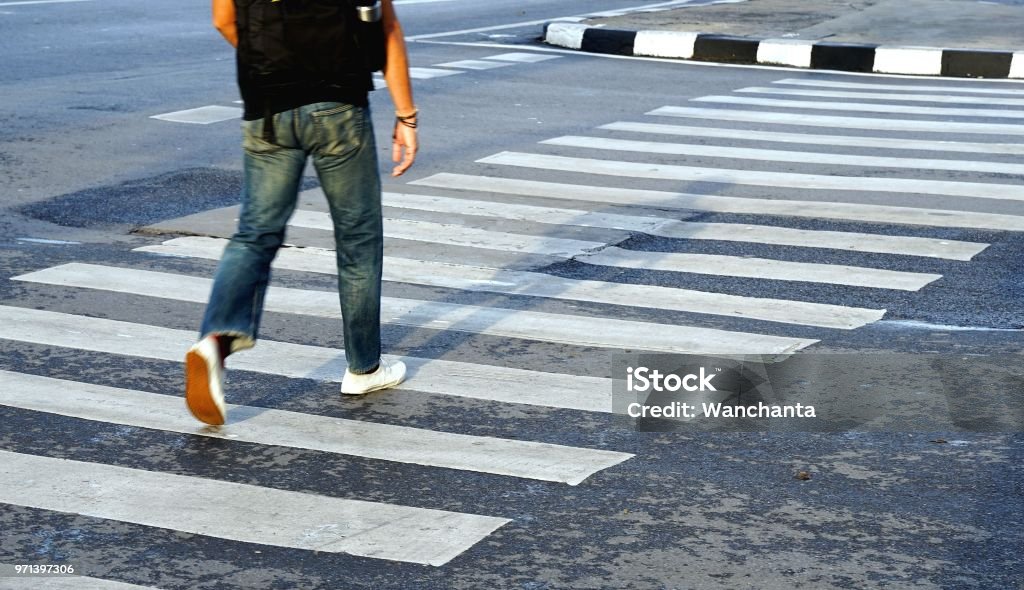 Man wearing white shoes and jean crossing the street crosswalk, Bangkok Thailand. Crosswalk Stock Photo