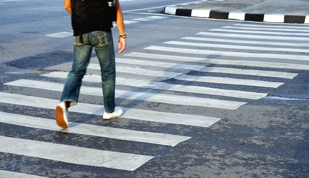 Man wearing white shoes and jean crossing the street crosswalk, Bangkok Thailand. stock photo