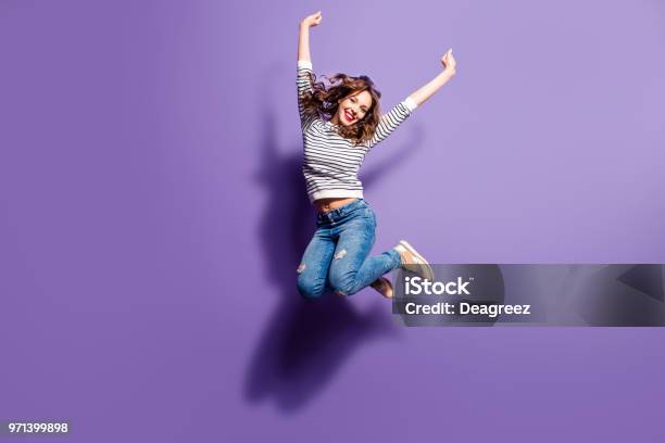 Portrait Of Cheerful Positive Girl Jumping In The Air With Raised Fists Looking At Camera Isolated On Violet Background Life People Energy Concept Stock Photo - Download Image Now