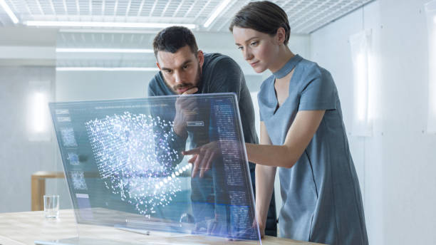 In the Near Future Male and Female Computer Engineers Talk While Working on the Transparent Display Computer. Screen Shows Interactive Neural Network, Artificial Intelligence Project, Futuristic User Interface. In the Near Future Male and Female Computer Engineers Talk While Working on the Transparent Display Computer. Screen Shows Interactive Neural Network, Artificial Intelligence Project, Futuristic User Interface. large screen stock pictures, royalty-free photos & images