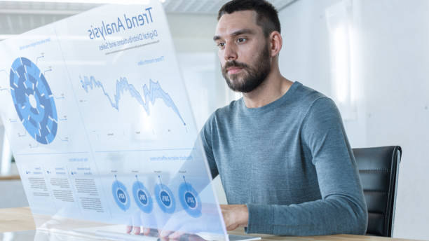 istock In the Near Future Successful Trader Works on Computer with Transparent Display that Shows Interactive Line Charts and Other Useful Information. His Office is Bright and Modern. 971403470