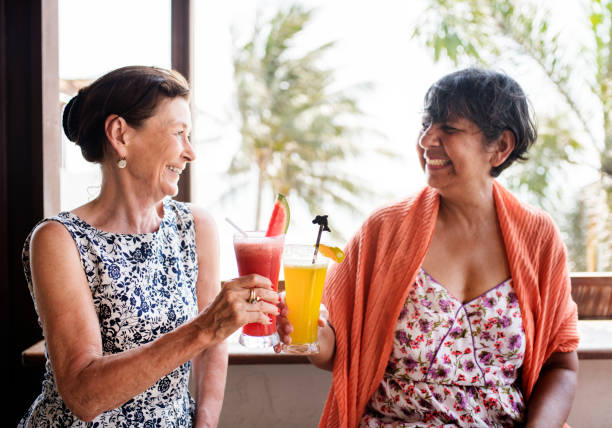 пожилые женщины, наслаждающиеся напитками в летнее время - party beach indian ethnicity adult стоковые фото и изображения