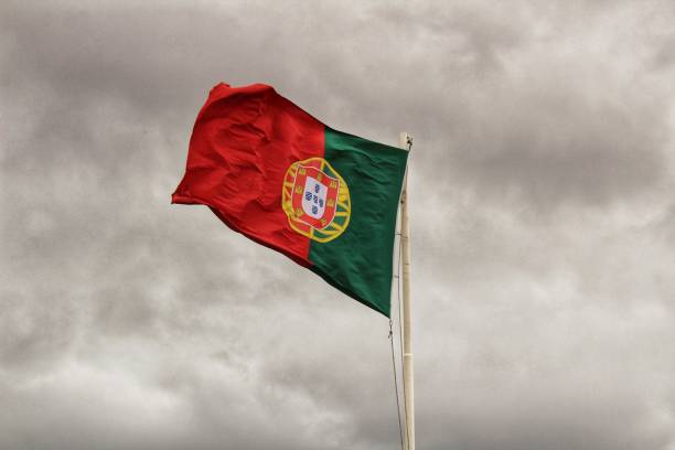 istock Portugal flag waving under cloudy sky 971404420