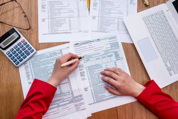 Top view on female hands filling 1040 tax form Top view on female hands filling 1040 tax form Digital Permit Book vs. Traditional Paper Systems stock pictures, royalty-free photos & images