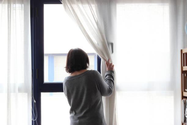 istock woman looking out the window 971409886