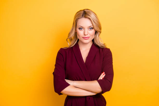 Portrait of pretty charming  woman in burgundy suit having her arms crossed looking at camera isolated on yellow background Portrait of pretty charming  woman in burgundy suit having her arms crossed looking at camera isolated on yellow background smirking stock pictures, royalty-free photos & images