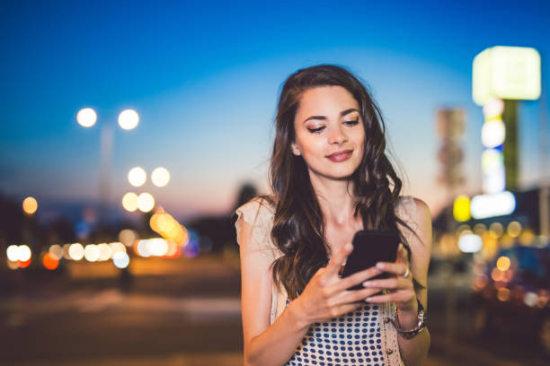 istock Young woman walking at night and using smart phone. 971423262