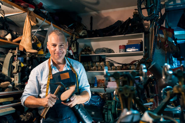 istock Concentrated man shoemaker at footwear workshop. 971436304