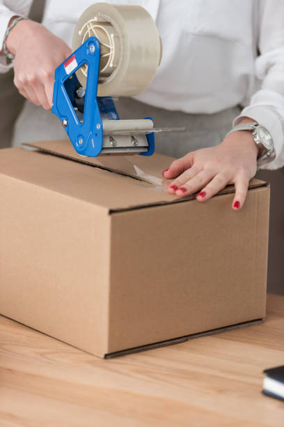 istock partial view of entrepreneur packing customers parcel with adhesive tape 971443624