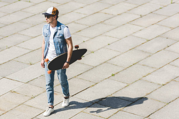 istock high angle view of handsome young man walking with skateboard in hand 971444586