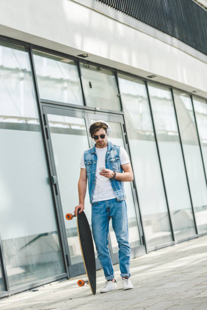 istock handsome young skateboarder with longboard using smartphone 971444736