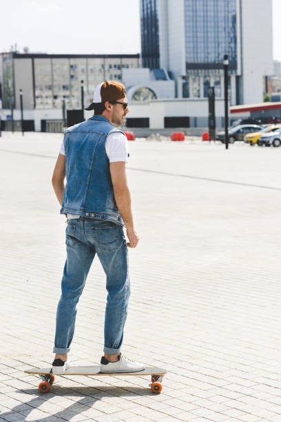 handsome young skateboarder riding longboard on city square