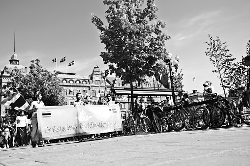 Members of Drakstaden Buddhistförening (Sundsvall Buddhist Association) in Thai national costume dance and parade with the association banner and with the national flags of Thailand and Sweden.  The parade is to celebrate Sweden's National Day (June 6th) in Sundsvall (north of Stockholm)