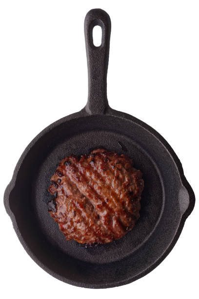 Food: fried homemade burger on a frying pan, isolated on white background