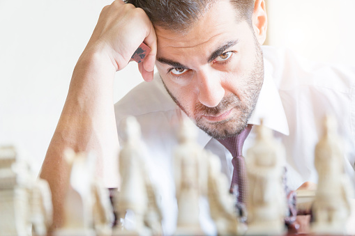 Businessman playing chess and staring carefully