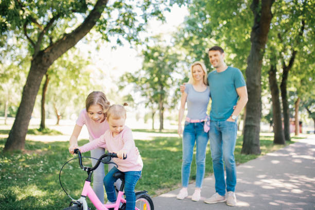 istock Siblings riding a bike, parents observing them 971494426