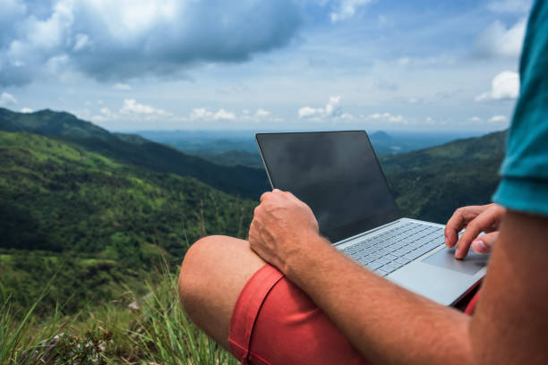 homme caucasien avec ordinateur portable assis sur le bord de la montagne d’ella avec une vue imprenable sur la vallée au sri lanka. - ella sri lanka photos et images de collection
