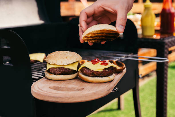 istock Chef serving hamburgers cooked outdoors on wooden board 971504196