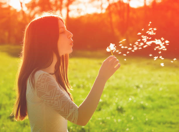 istock woman blowing on a dandelion 971512264
