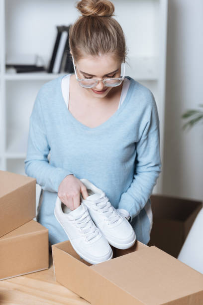 istock entrepreneur putting shoes into cardboard box while packing customers purchase at home office 971529280