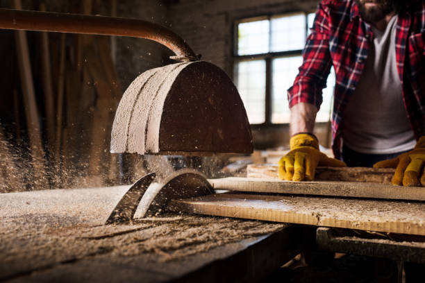 istock cropped image of carpenter in protective gloves  using machine saw at sawmill 971544838