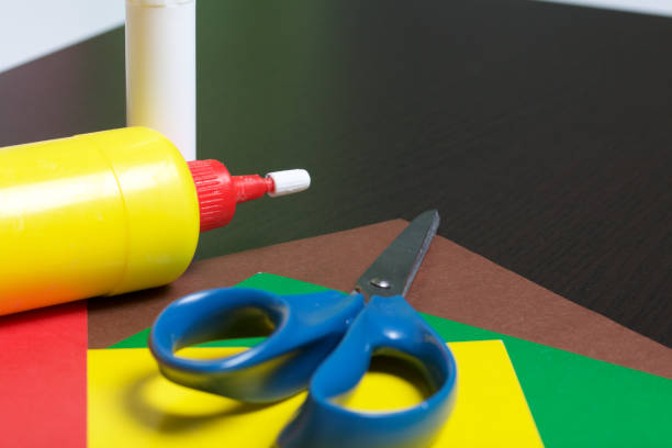 istock Lessons in applique. Necessary items: glue, colored paper and scissors lie on the dark surface of the table. 971544912