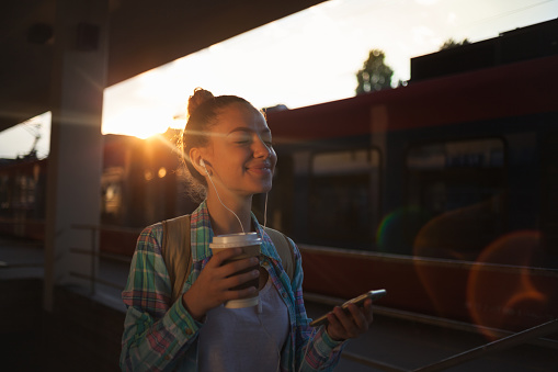 Close up of Teenage girl listening music on train station