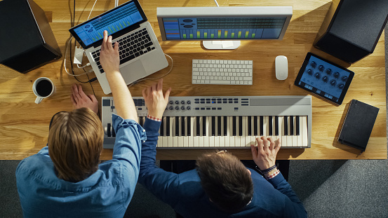 Top View of Two Audio Engineers Working in Their Sunny Studio. They Play on a Musical Keyboard and Experiment with Sound.