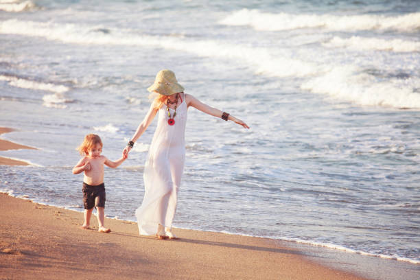 istock Mother and child walking on the beach 971560210