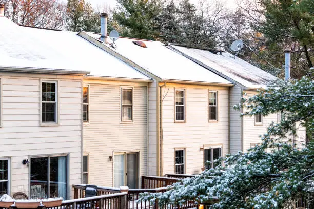 House townhomes rowhouses rooftop roof with chimneys covered in white winter snow, cold season in Virginia