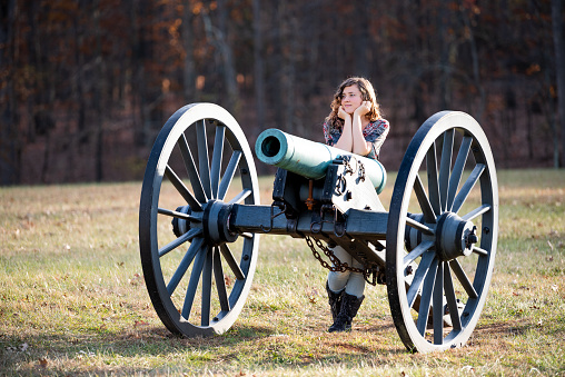 Young happy woman standing by cannon in Manassas National Battlefield Park in Virginia where Bull Run battle was fought