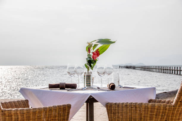 istock Close-up on a dinner table by the beach with wine glasses and flower 971596814