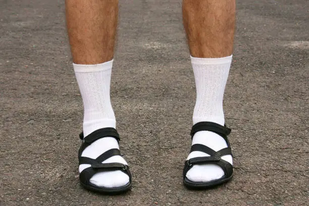 The lower part of men's feet in white socks and sandals