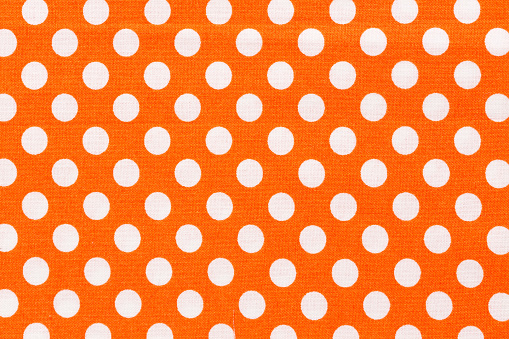 Close up of orange and white distressed polka dots background. Hi res