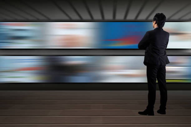 Businessman standing looking at the TV screen